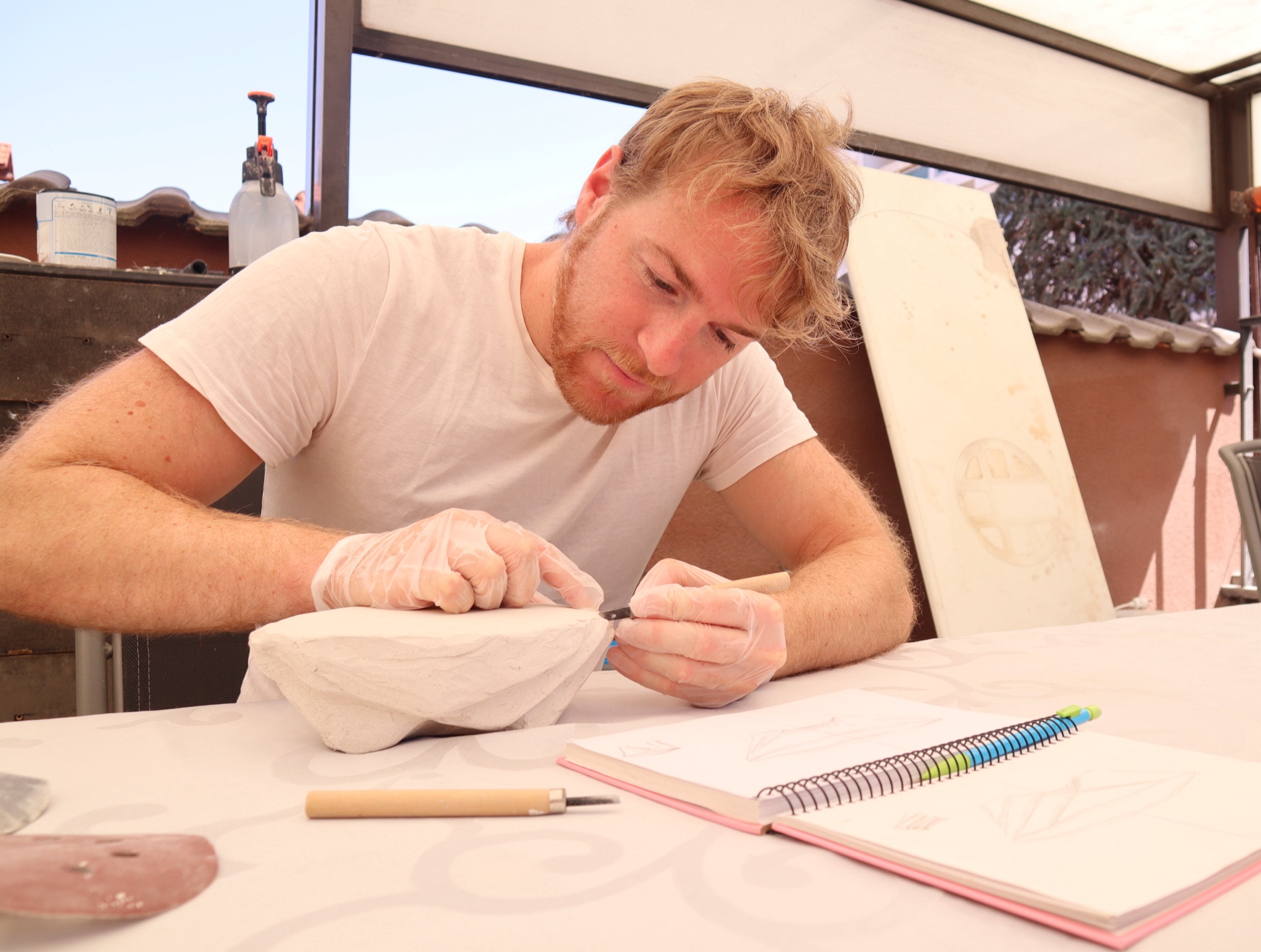 Louis Michel à l'atelier, en train de dessiner une esquisse de table sculptée