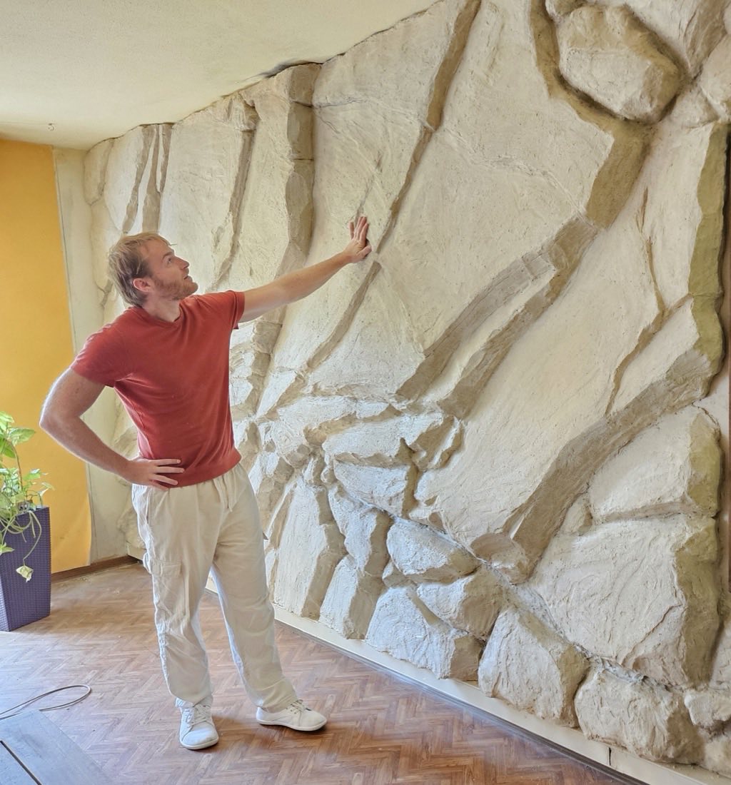 Louis Michel, la main pos&eacute;e sur le mur effet roche de 2,40 m de haut qu&rsquo;il vient de terminer
