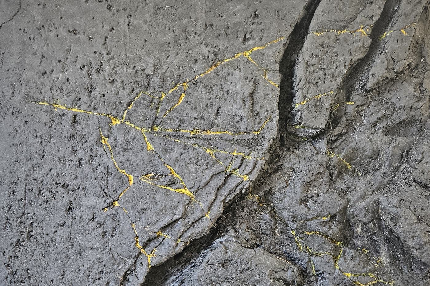 Mur effet roche noire sculpté à la main, faille traversante et veines dorées
