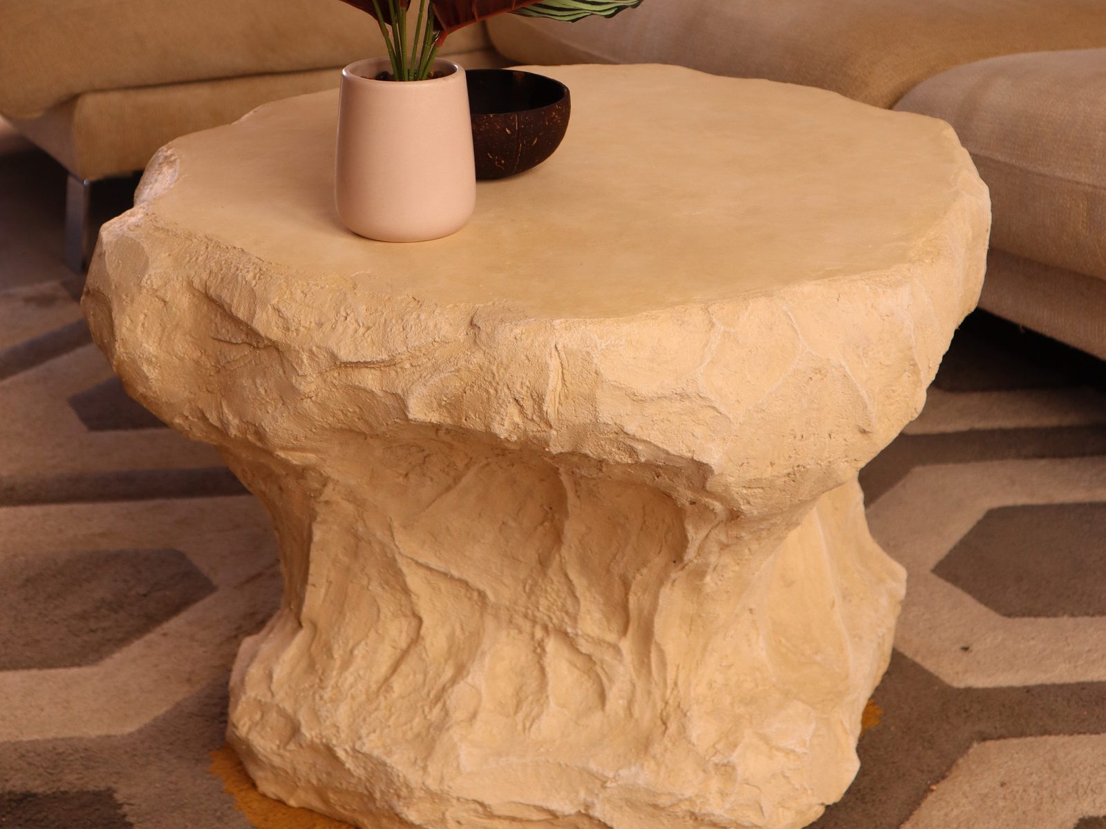 Table d'appoint effet travertin au bord d'un canapé, vue de trois quarts